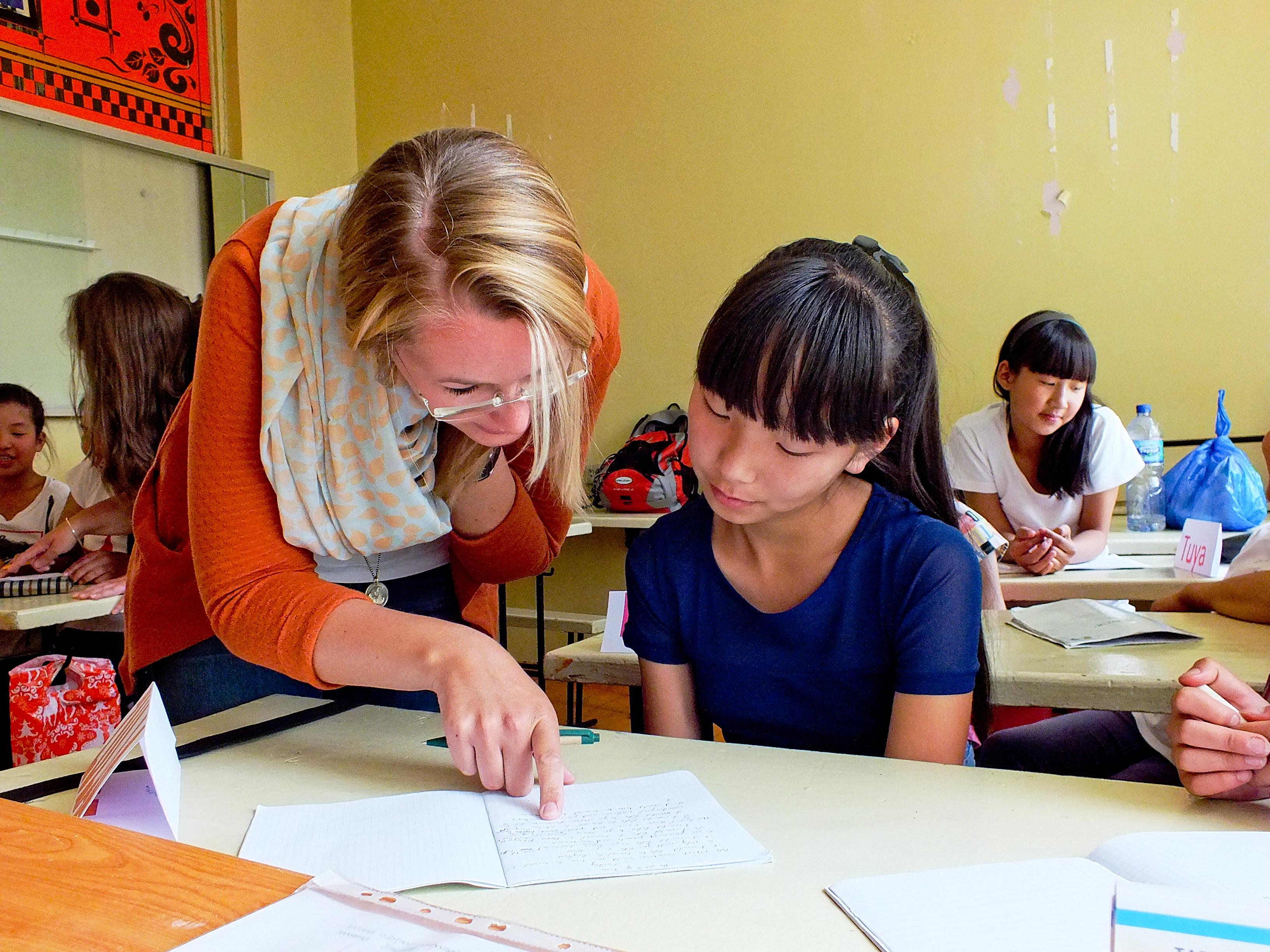A volunteer teaching English in Mongolia helps a young girl with her homework A Projects Abroad volunteer helps her student with her classwork at a teaching placement in Mongolia